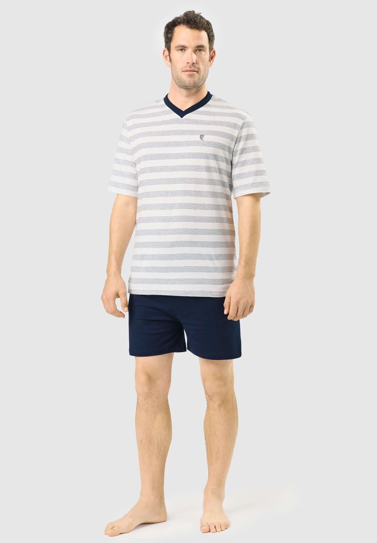 Pijama de hombre con camiseta de rayas gris/blanco, cuello pico azul marino y pantalón corto azul liso.