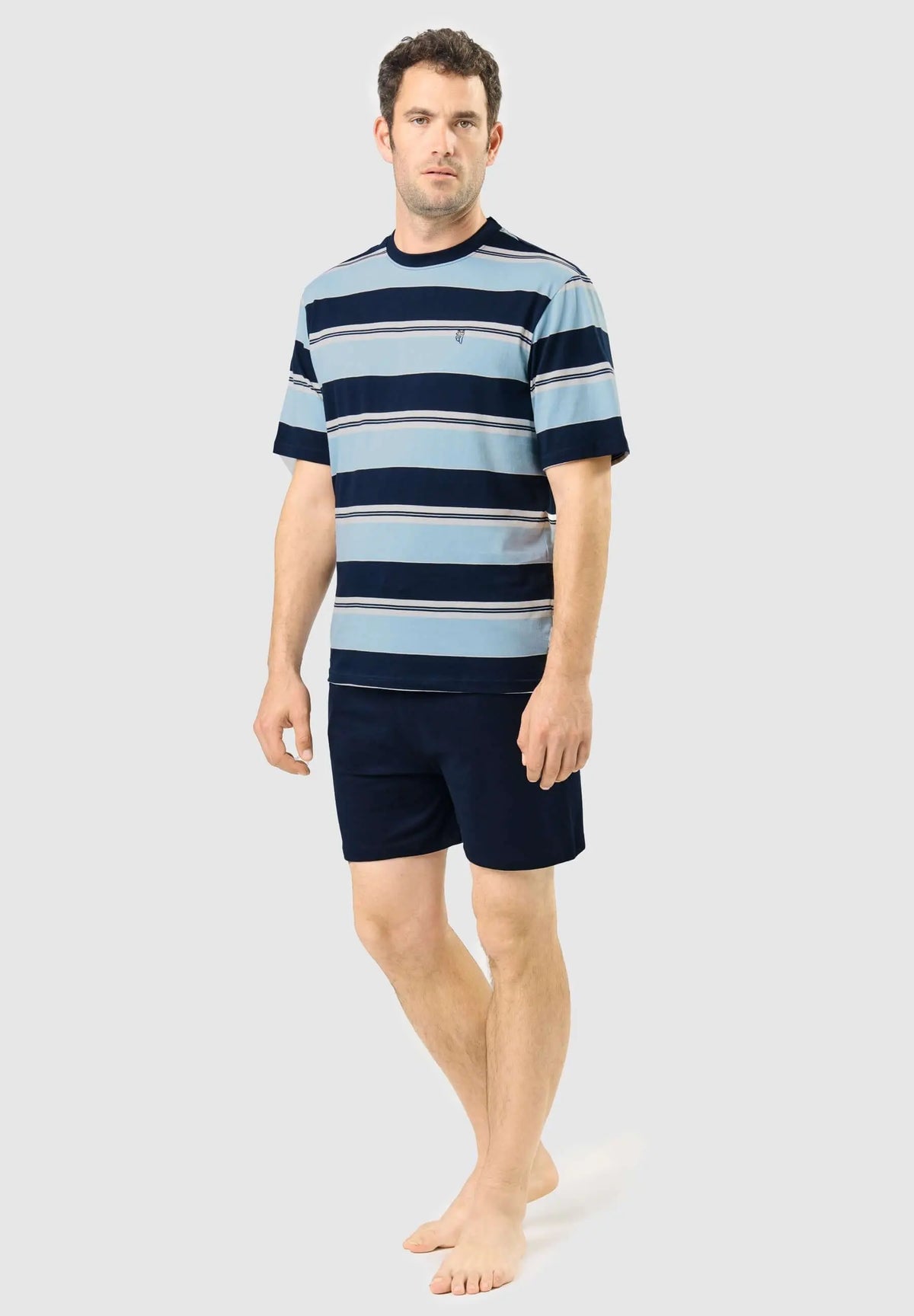 Modelo con pijama corto de hombre: camiseta azul de rayas horizontales y pantalón corto liso azul marino.
