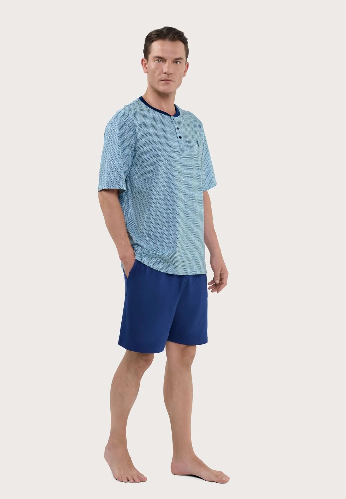 Hombre con pijama corto de verano en punto de algodón azul, camiseta estampada con tapeta y pantalón liso cómodo.