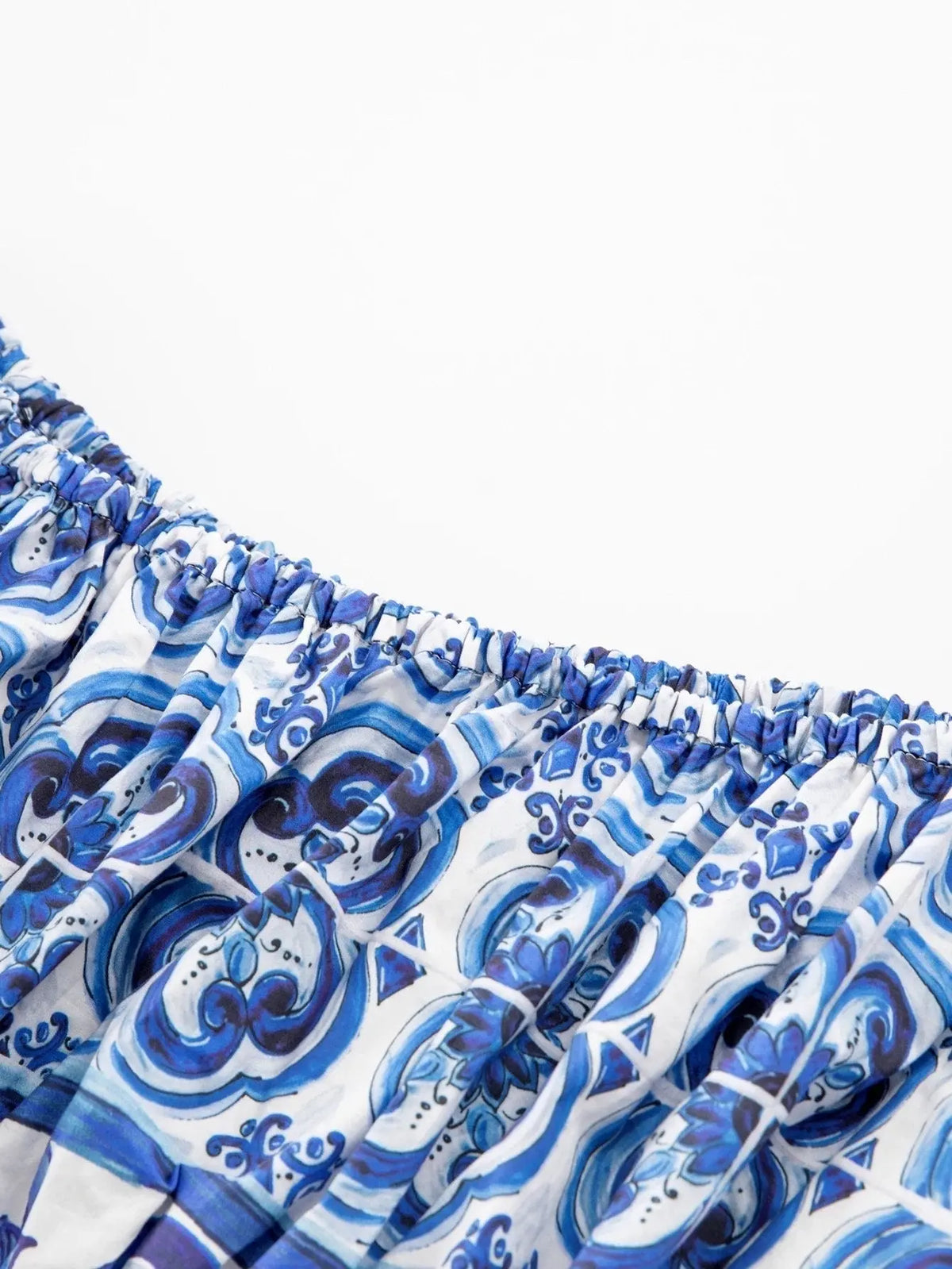 Blue and white patterned off-shoulder dress with elastic neckline, featuring intricate swirl designs in lightweight fabric.