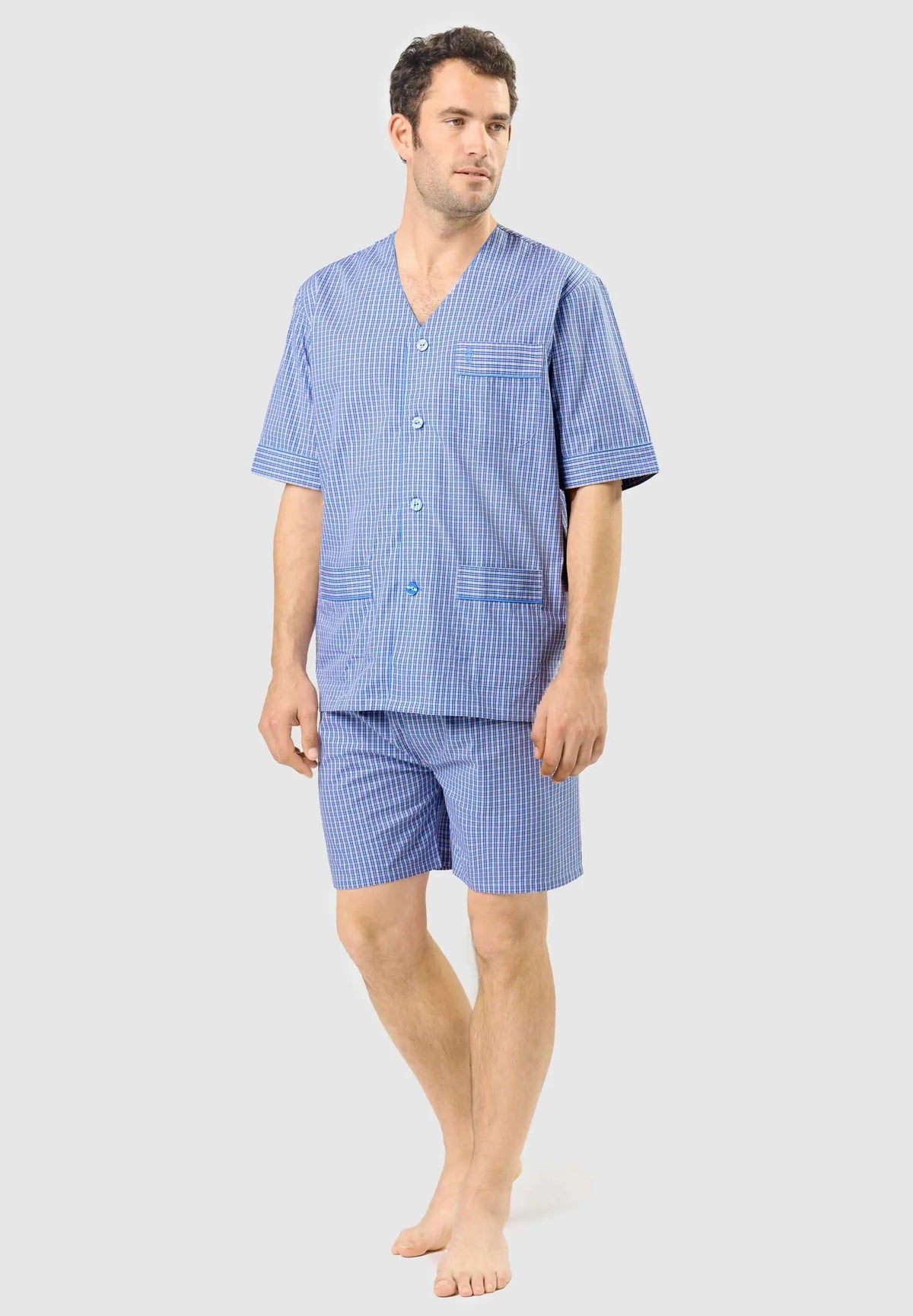 Hombre con pijama corto de cuadros azules, cuello en pico, botones y bolsillos, tejido de algodón, estilo veraniego.