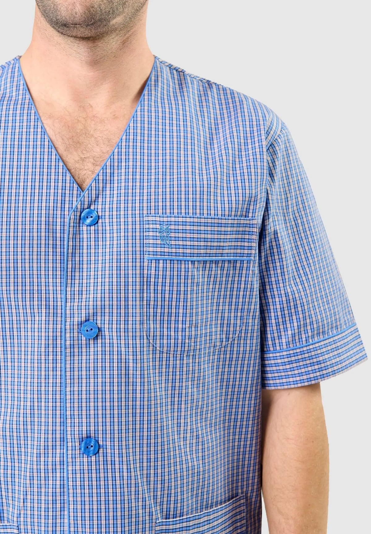 Pijama de hombre azul a cuadros, cuello pico, botones, manga corta y bolsillo con logo bordado de El Búho Nocturno.