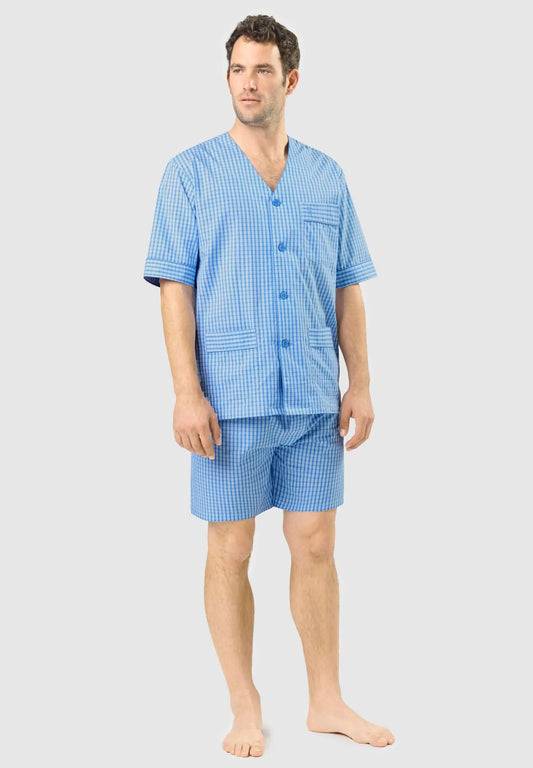 Hombre con pijama corto de cuadros azules, cuello en pico, botones y bolsillos, tejido ligero de verano.