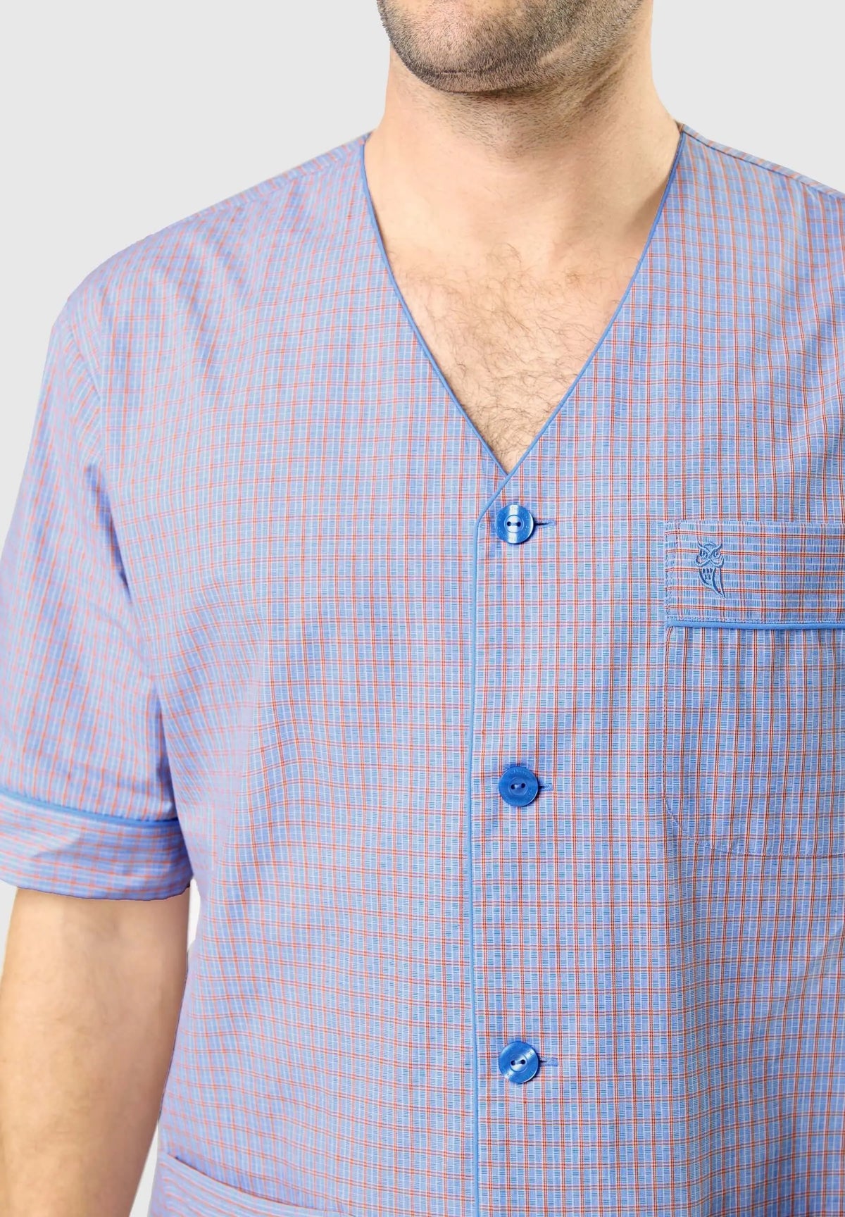 Pijama de hombre azul y naranja a cuadros con cuello en pico, botones, manga corta y bolsillo con logo de búho bordado.