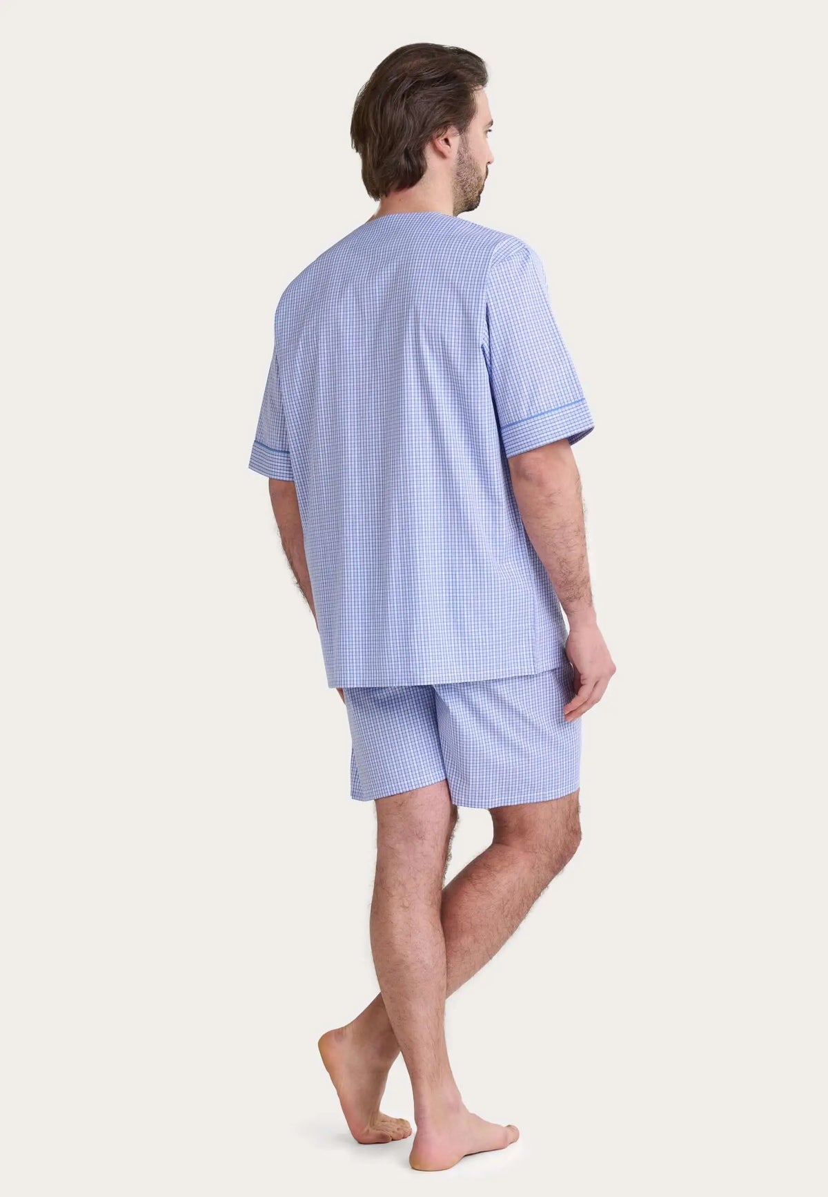 Hombre de espaldas con pijama corto de cuadros azules y blancos de manga corta y cuello redondo.