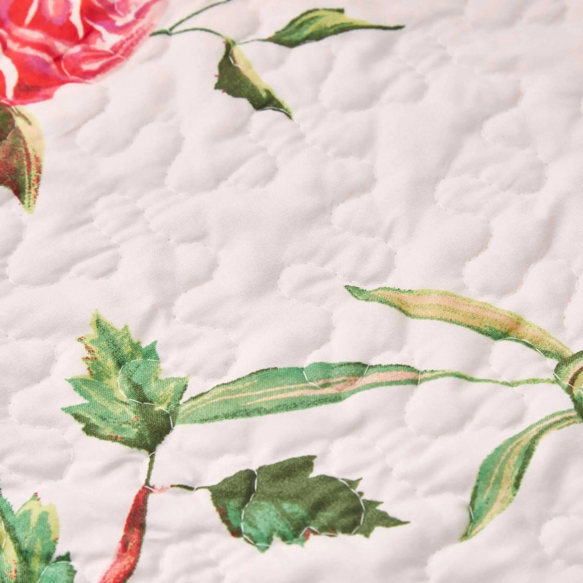 Quilted white fabric table runner with a romantic floral pattern of pink roses and green leaves.