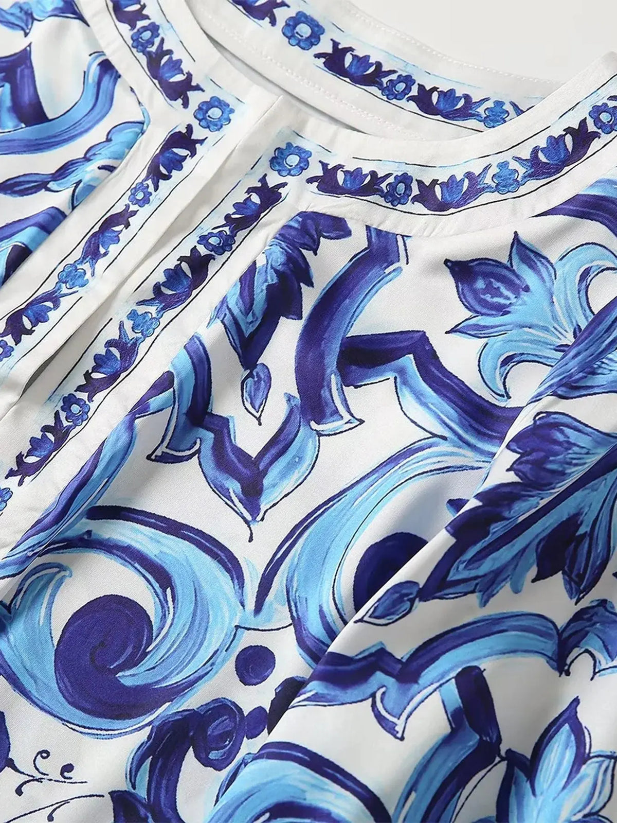 Blue and white floral print blouse with intricate design and button details, perfect for casual or semi-formal wear.