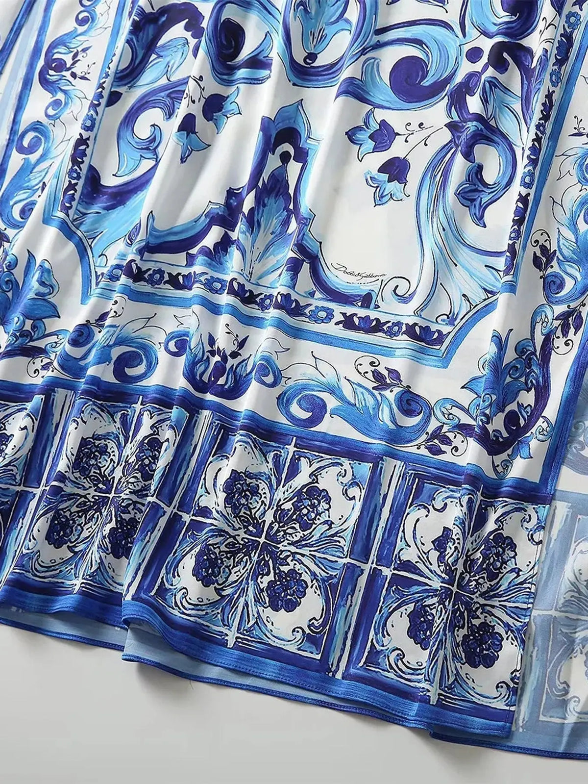 Blue and white patterned silk scarf featuring intricate floral designs and elegant baroque motifs.