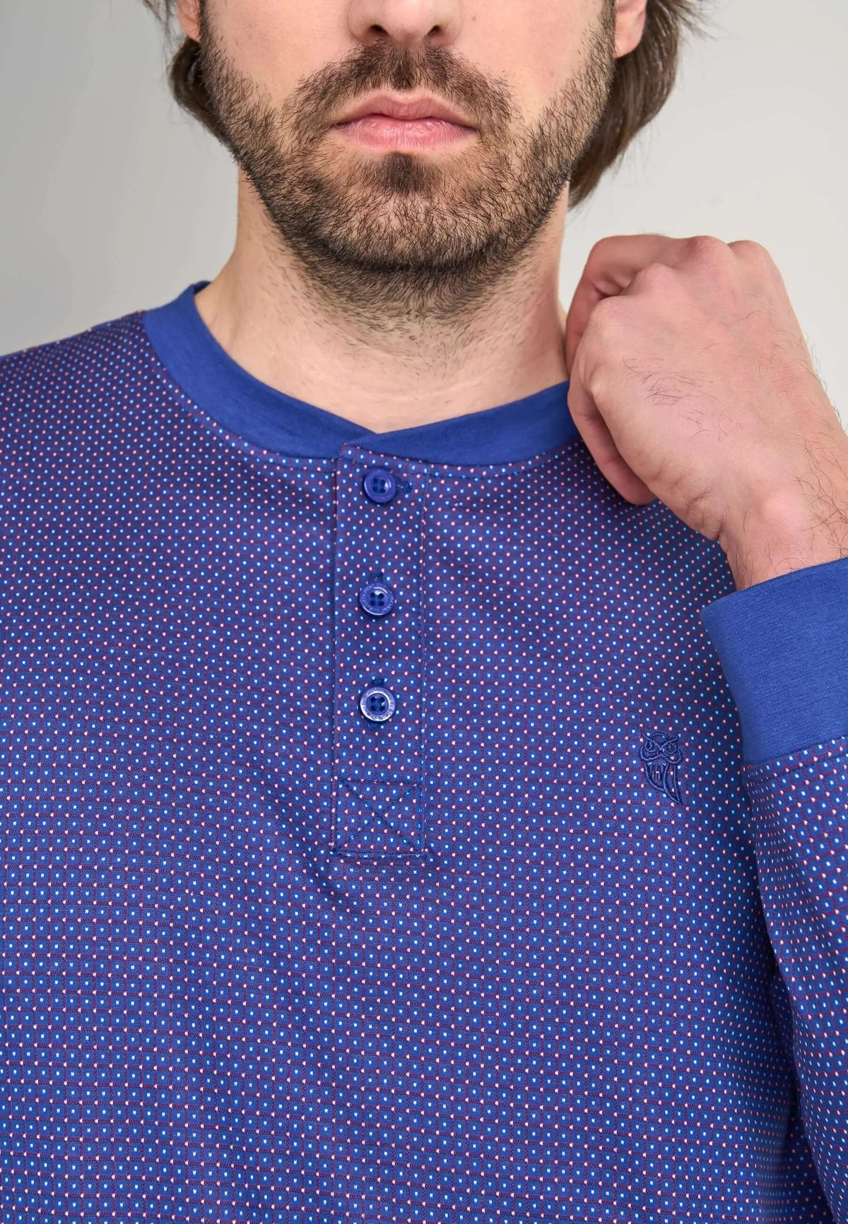 Pijama azul con tapeta de botones, estampado geométrico de puntos blancos y logo de búho bordado, puesto en modelo.