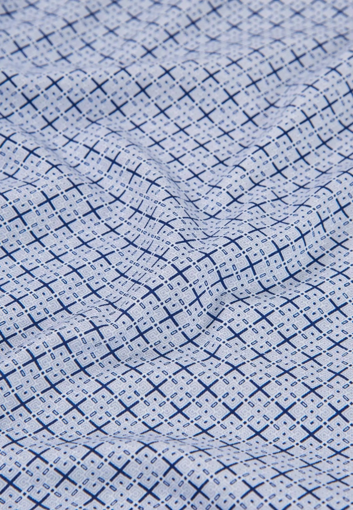 Tejido de punto blanco con estampado geométrico de cruces y pequeños detalles en azul marino sobre fondo claro.