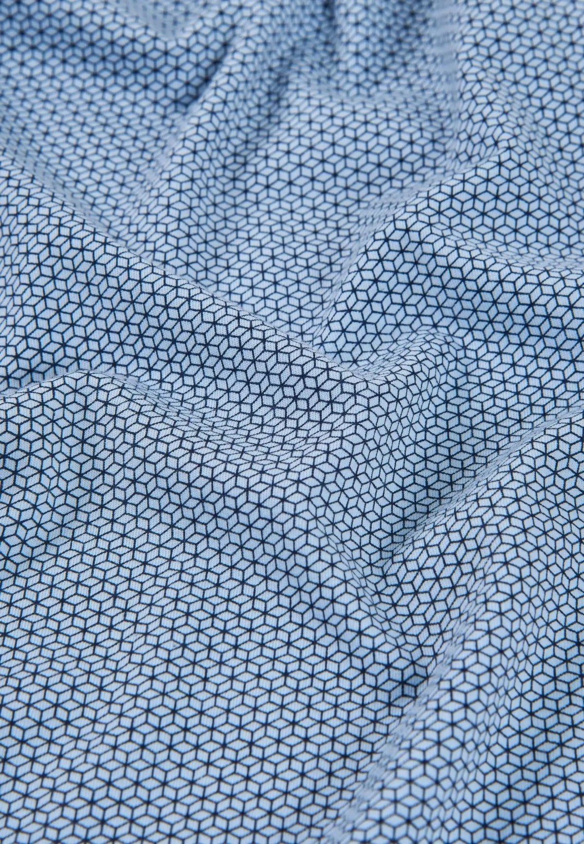 Detalle de tejido de algodón azul con estampado geométrico de hexágonos en color negro para pijama de hombre.