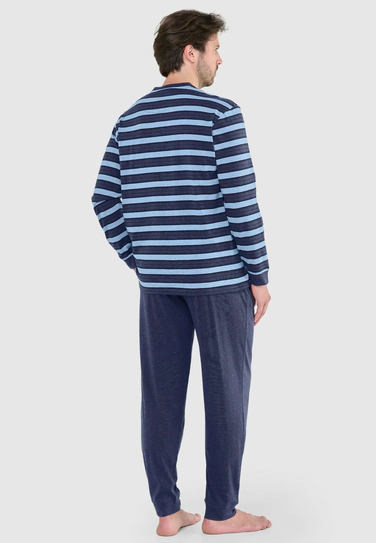 Pijama de hombre con camiseta de rayas azules y pantalón liso azul marino en tejido de punto, visto desde atrás.