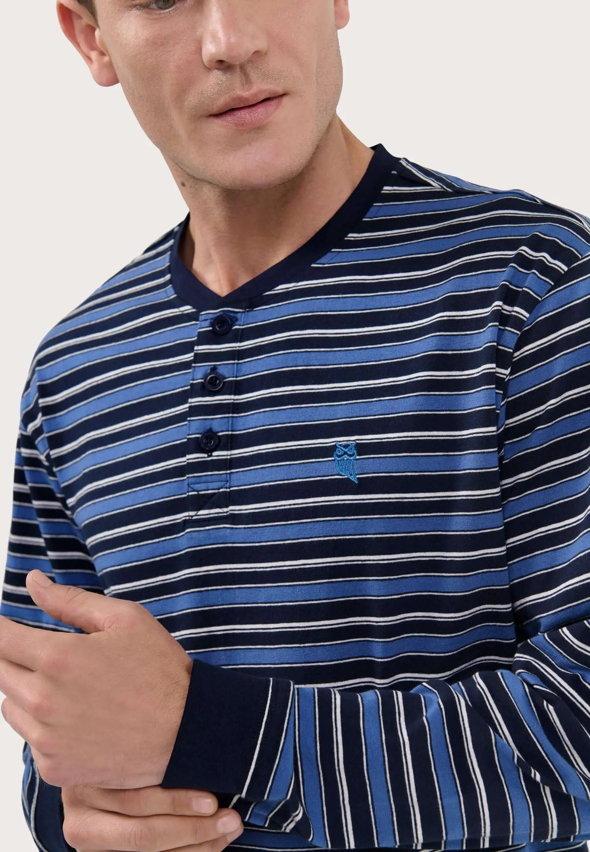 Pijama de hombre a rayas azules y blancas, cuello con tapeta de tres botones, puños lisos y logo bordado de búho.