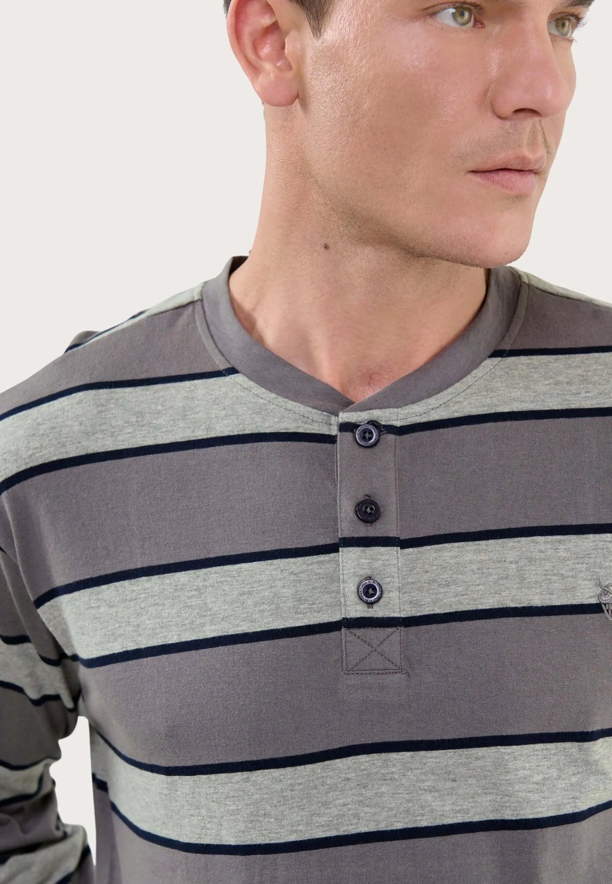 Pijama hombre El Búho Nocturno: camiseta gris a rayas horizontales, cuello redondo y tapeta con tres botones oscuros.
