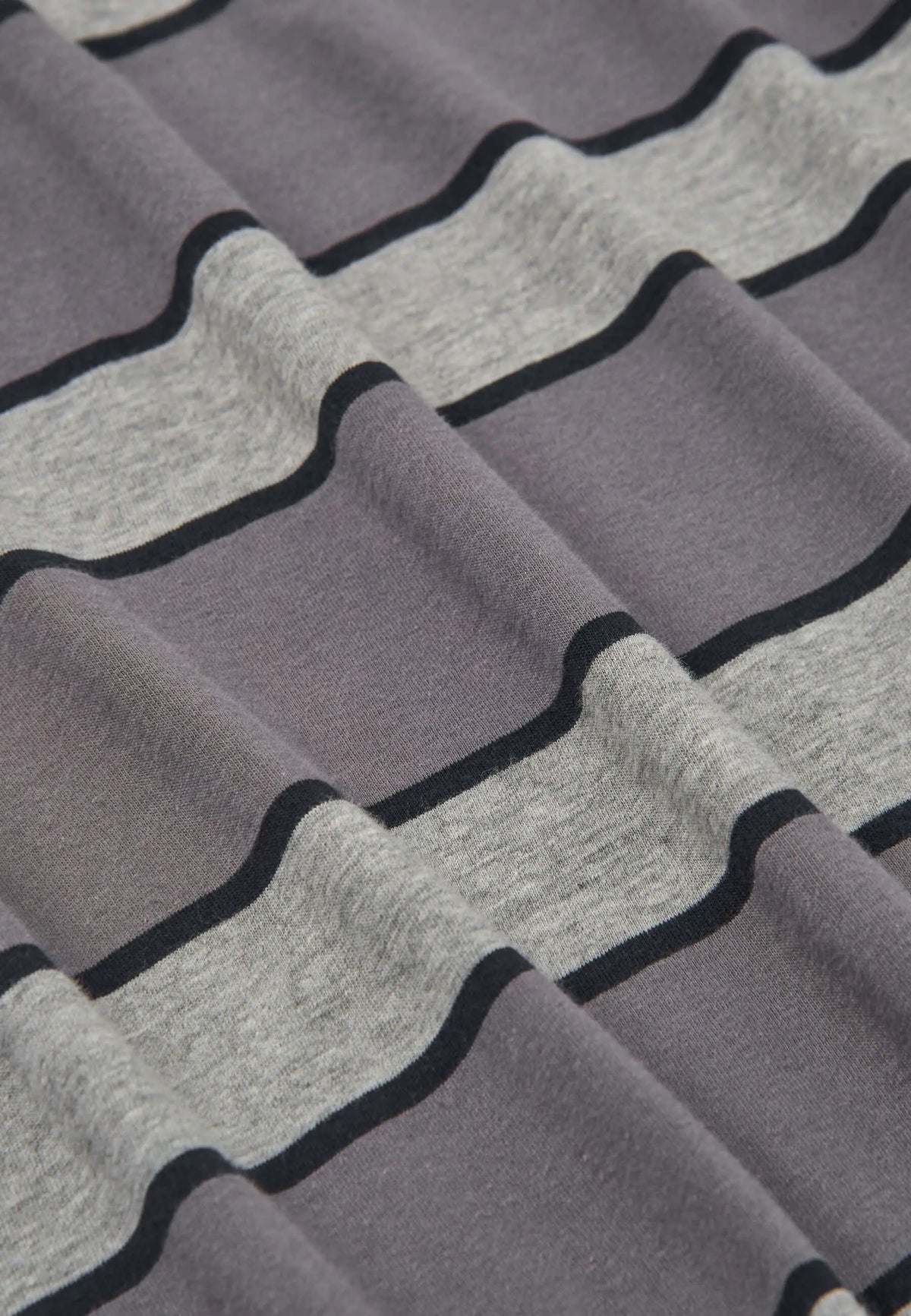 Detalle de tejido de punto de pijama con rayas horizontales grises y negras, textura suave y pliegues naturales.