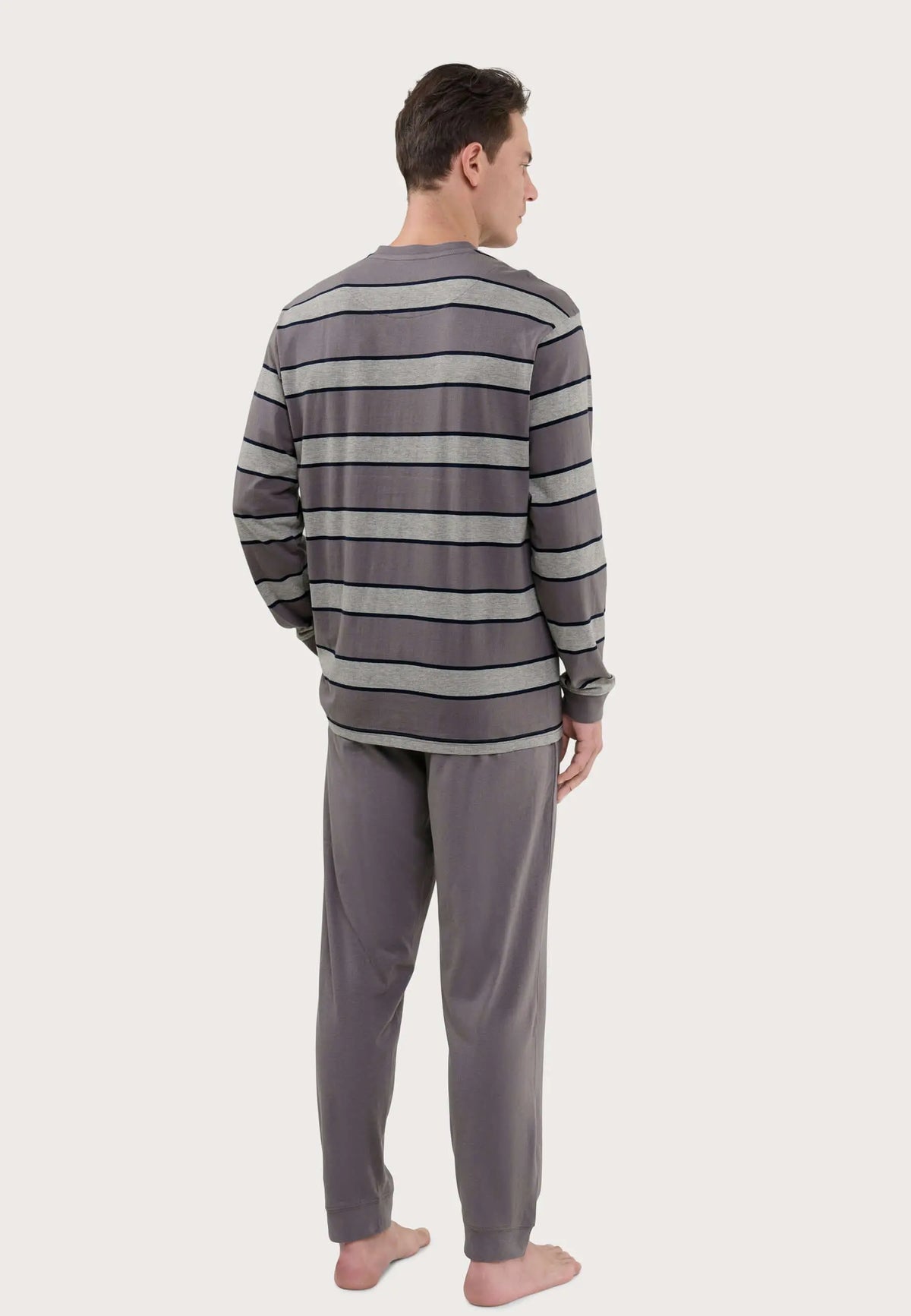Pijama de hombre largo, camiseta a rayas grises y pantalón liso de punto gris, visto desde la espalda en modelo.