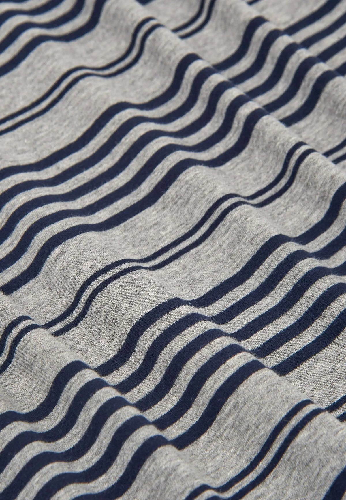 Tejido de punto gris con rayas horizontales azul marino en primer plano, mostrando textura suave y pliegues.