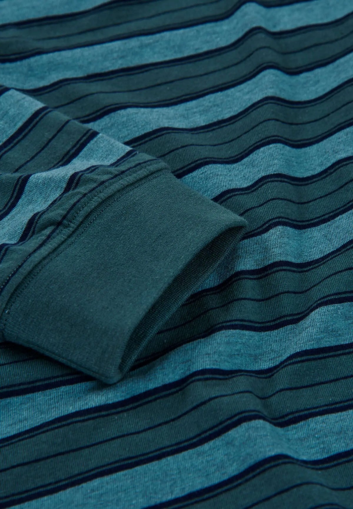Detalle de pijama de hombre en punto algodón verde con rayas horizontales y puño elástico en la manga.