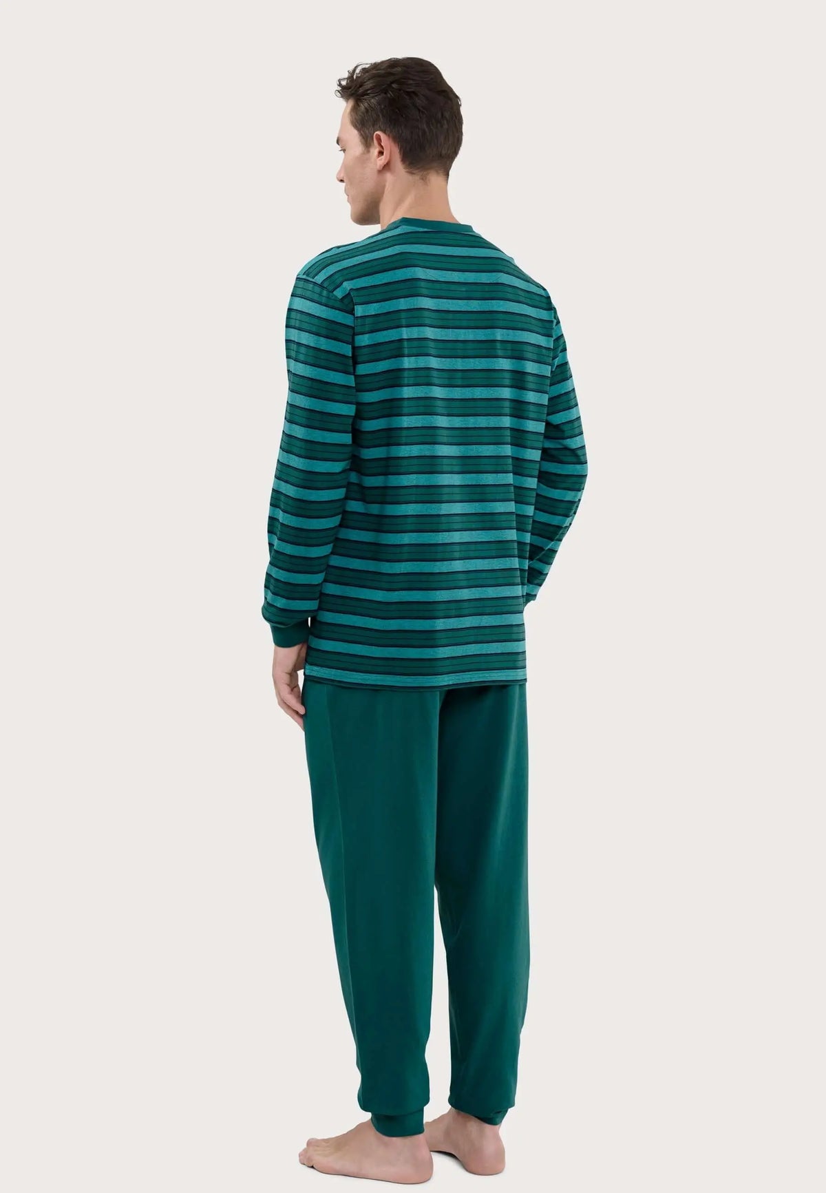 Hombre de espaldas vistiendo pijama largo: camiseta de rayas horizontales verdes y pantalón liso en verde oscuro.