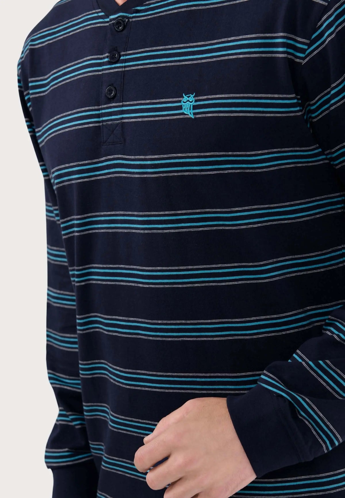 Pijama hombre azul marino a rayas con tapeta de tres botones, tejido de punto y logo de búho bordado en turquesa.