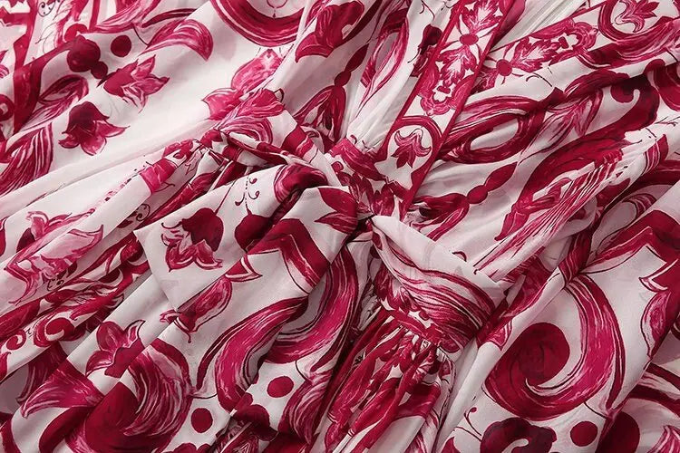 Red and white floral print dress with a cinched waist and flowing fabric, perfect for summer events.