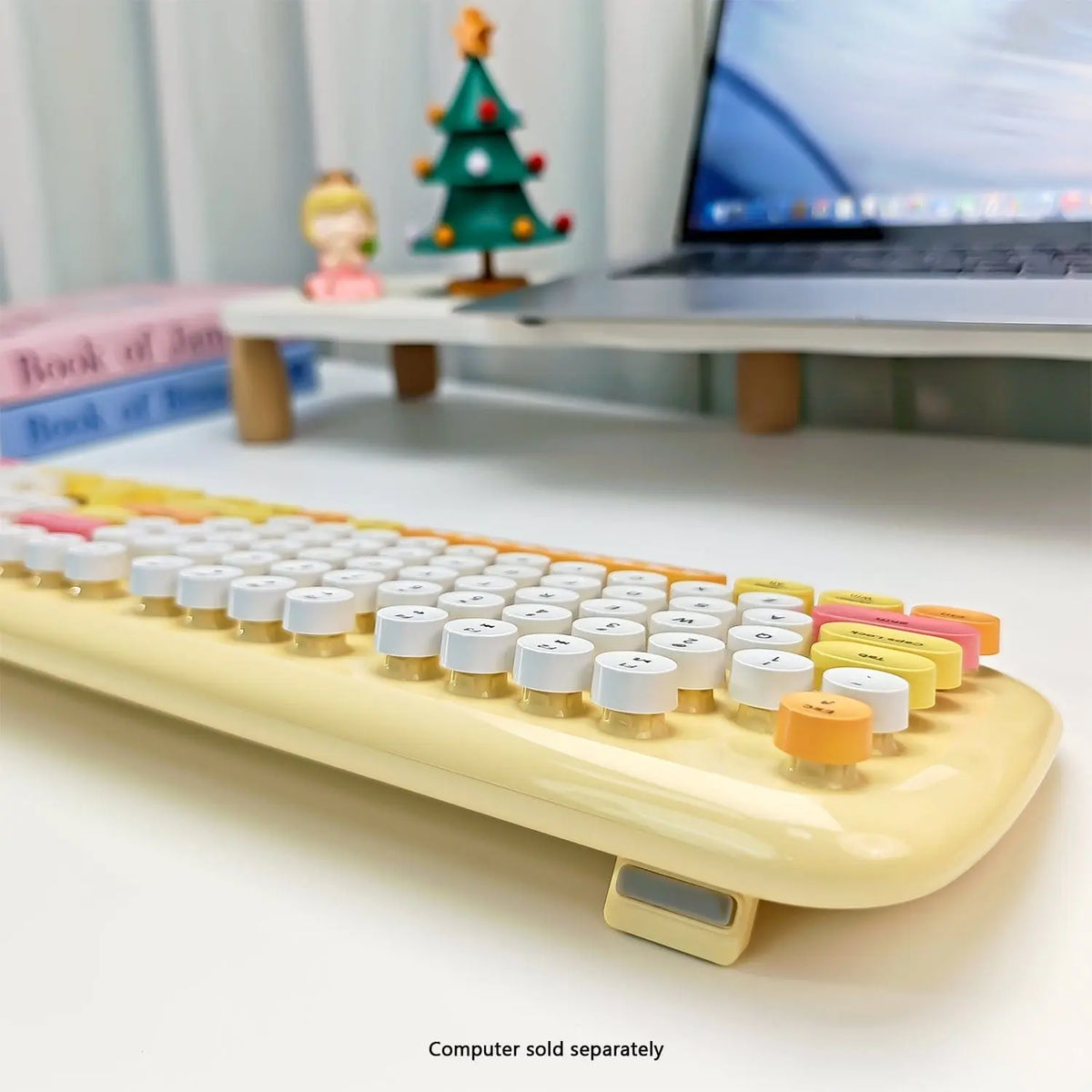 Pastel yellow wireless keyboard with colorful, round typewriter-style keys on a white desk.