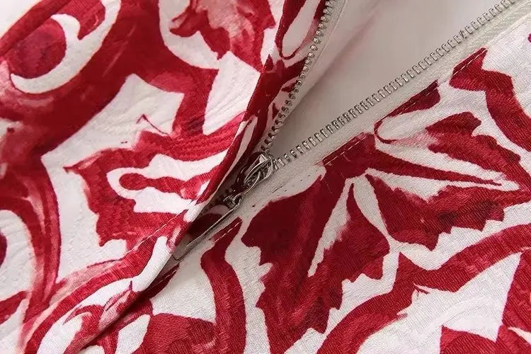 Red and white floral patterned fabric close-up with a zipper detail, perfect for stylish apparel or home decor.