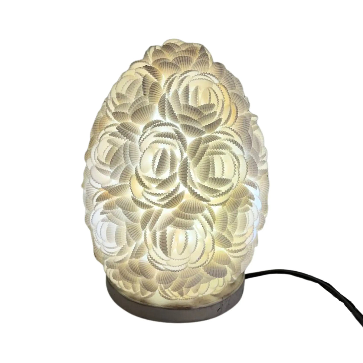 Lámpara boho ovalada de 15 cm hecha a mano con conchas marinas blancas, emitiendo una luz cálida y decorativa.