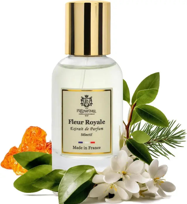 Glass perfume bottle with gold cap and label, surrounded by white jasmine flowers, green leaves, and orange resin.