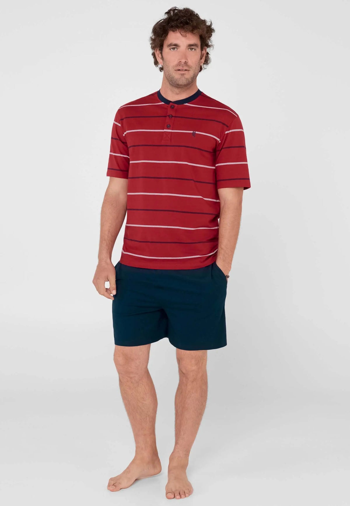 Hombre con pijama corto: camiseta roja de rayas con botones y pantalón azul marino liso de punto.