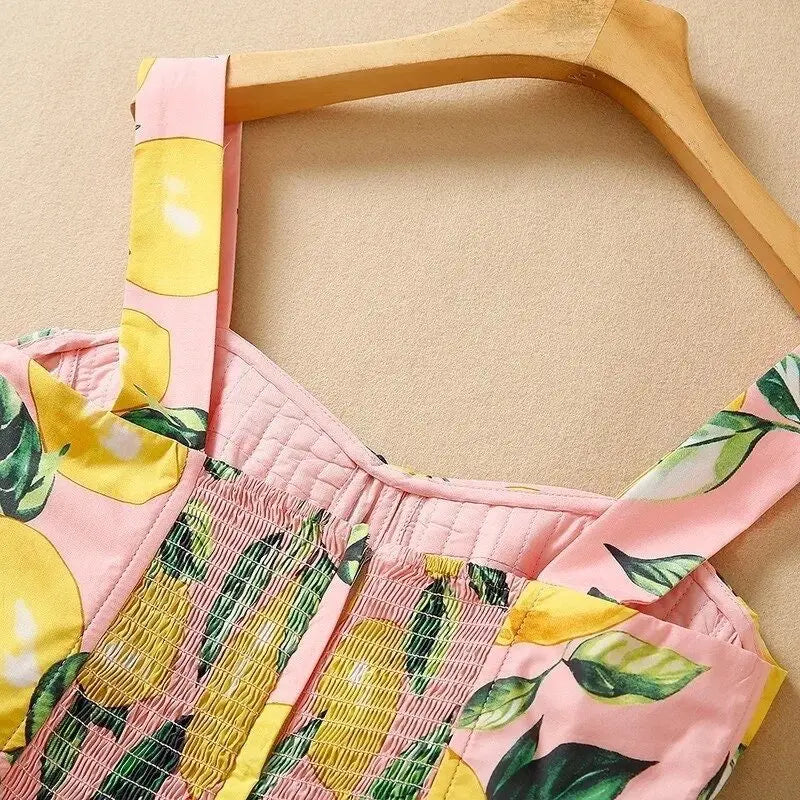Pink lemon-print dress with smocked bodice and wide straps, perfect for summer outings.