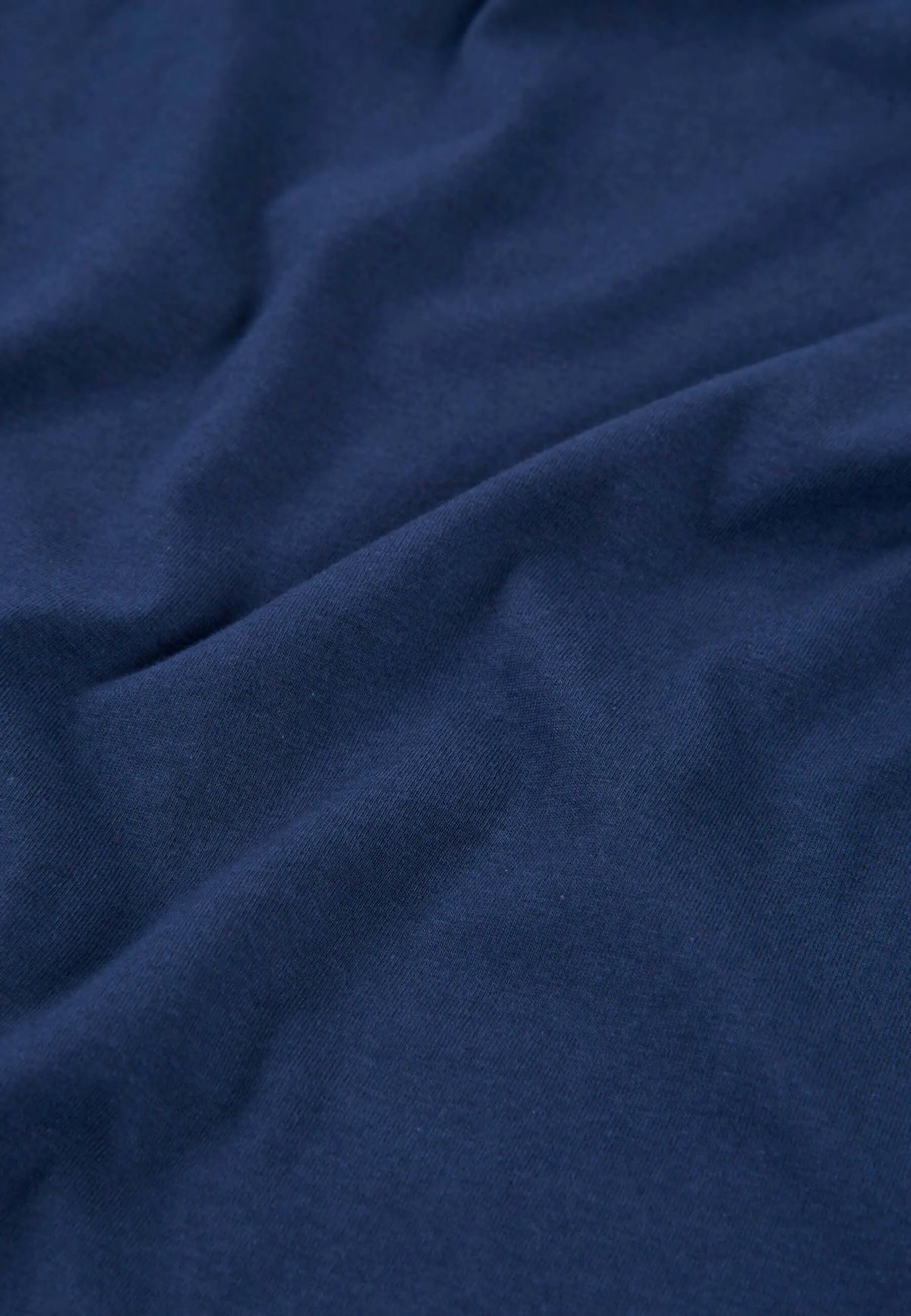 Detalle de tejido suave de algodón azul para camiseta de pijama de hombre, acabado liso y confortable.