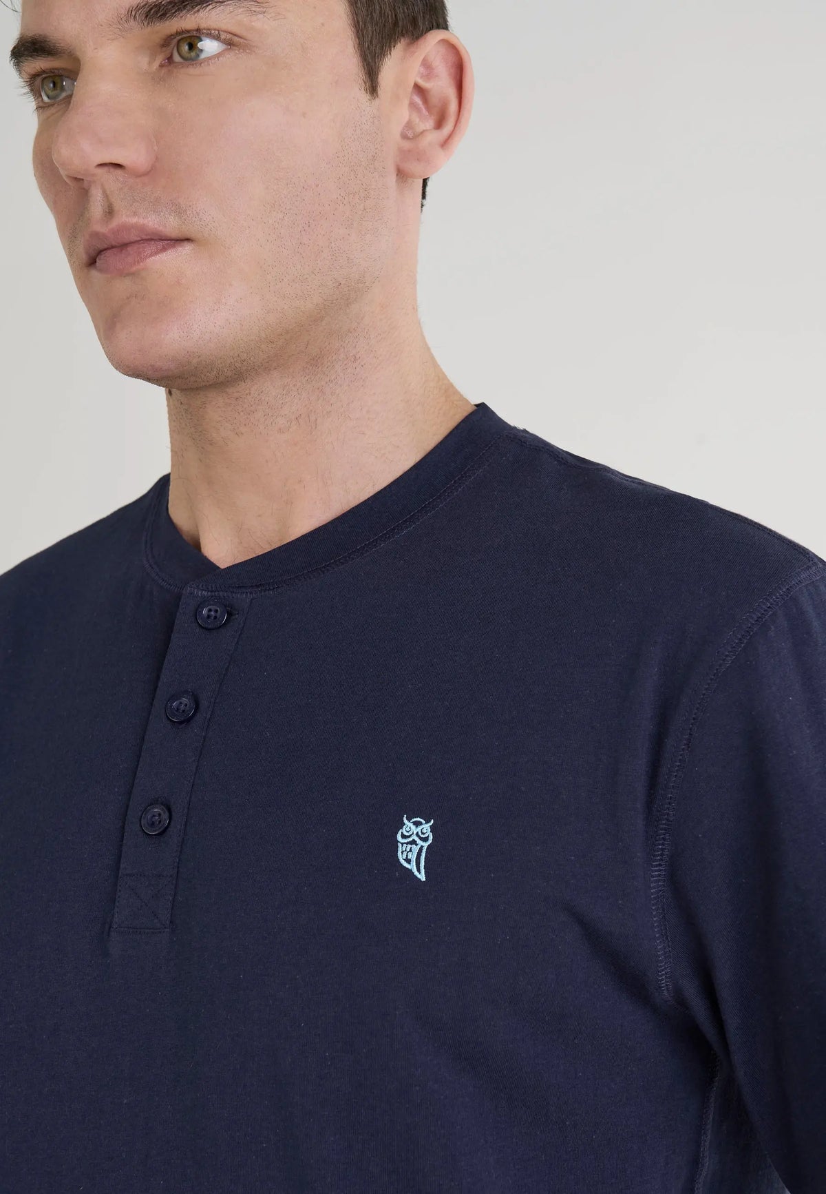 Camiseta masculina de algodón azul marino con botones y diseño bordado en el pecho. Estilo casual y moderno.