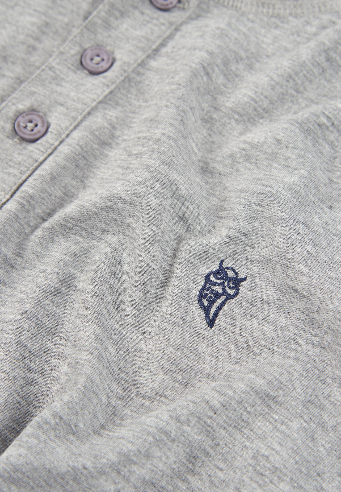 Camisa de algodón gris claro con botones morados y bordado de búho en el pecho. Estilo casual y cómodo.