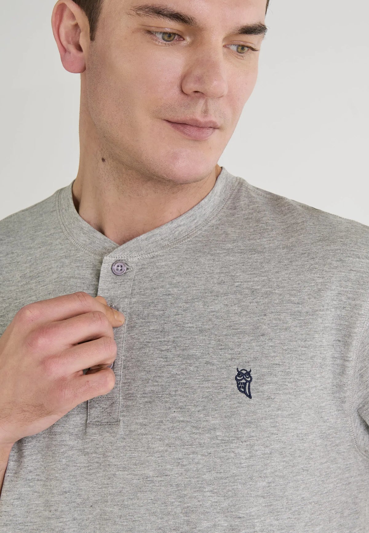 Camiseta masculina gris claro de algodón con botones y logo bordado en azul marino. Estilo casual y moderno.