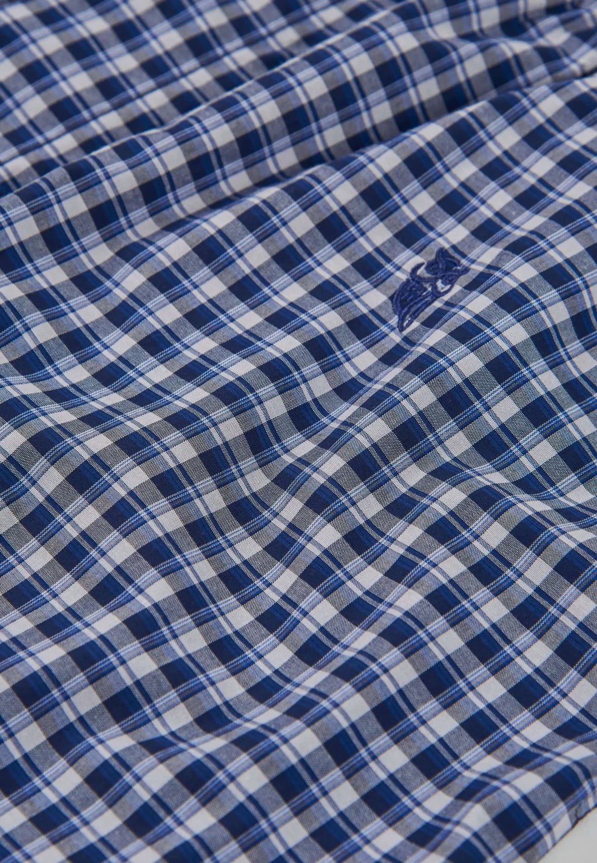 Detalle de pantalón de pijama de hombre en popelín de algodón con estampado de cuadros azul y blanco.