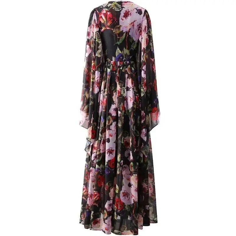 Flowy black floral maxi dress with long sleeves and an open back, featuring vibrant pink and red blooms on sheer fabric.