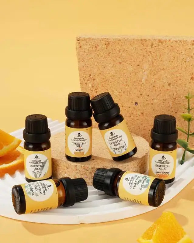 Six amber glass essential oil bottles with black caps and yellow labels, displayed on white and textured stone platforms.
