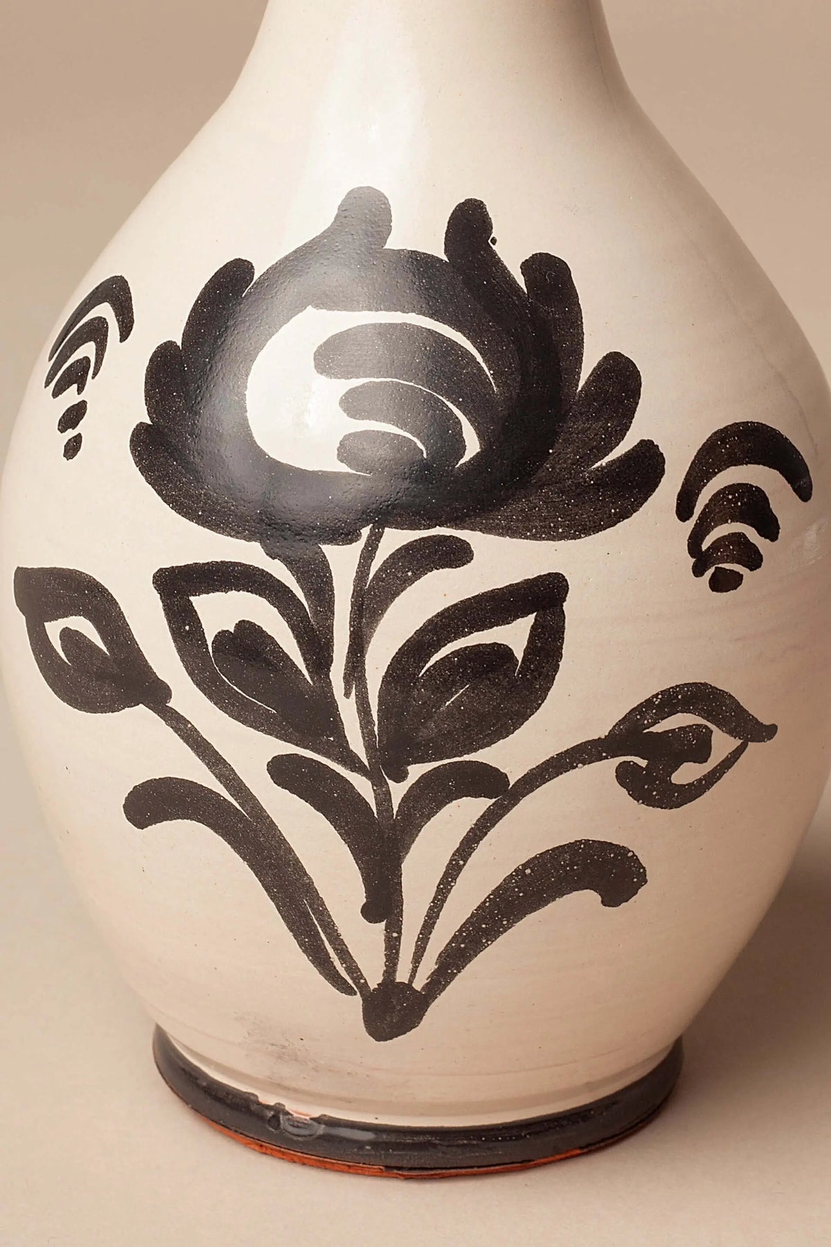 Aceitera de cerámica color crema con diseño floral pintado a mano en negro, de forma redondeada y acabado artesanal.