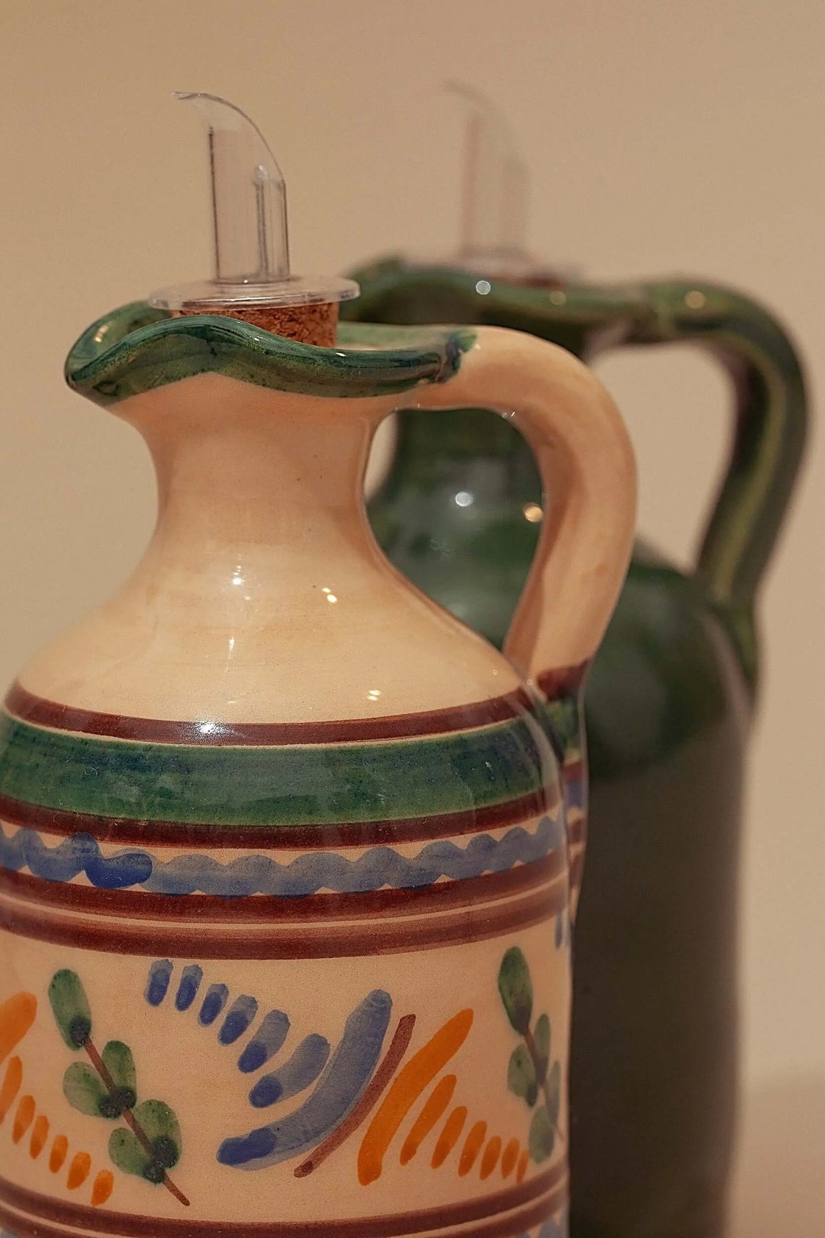 Dos aceiteras de cerámica artesanal con decoraciones pintadas a mano, tapón dosificador y diseño rústico tradicional.