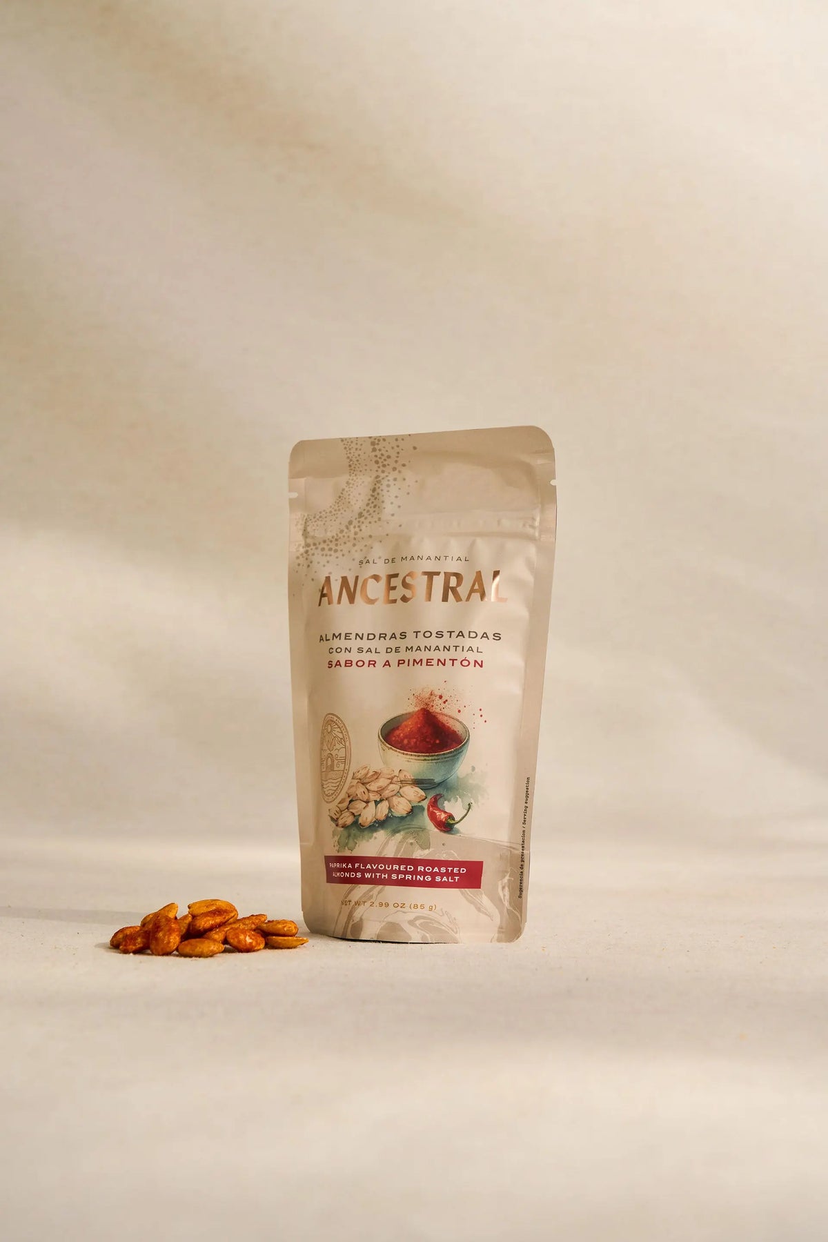 Stand-up pouch of paprika-flavored roasted almonds with spring salt, next to a small pile of the toasted nuts.