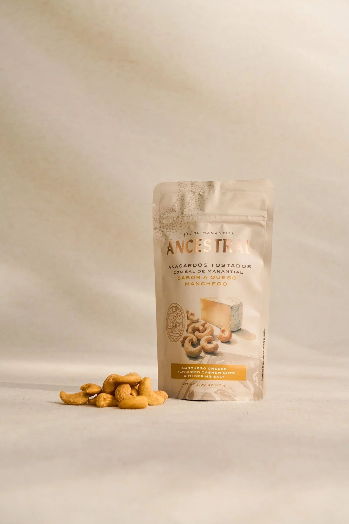 A pouch of Manchego cheese flavored cashews with spring salt, featuring a beige design and a small pile of nuts.