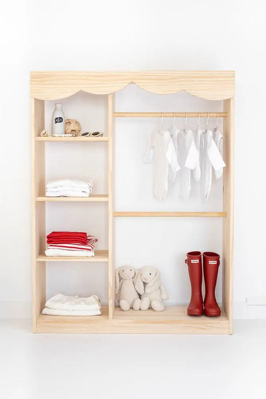 Armario de madera clara con estantes y perchas, incluye ropa blanca y roja, y botas rojas. Ideal para niños.
