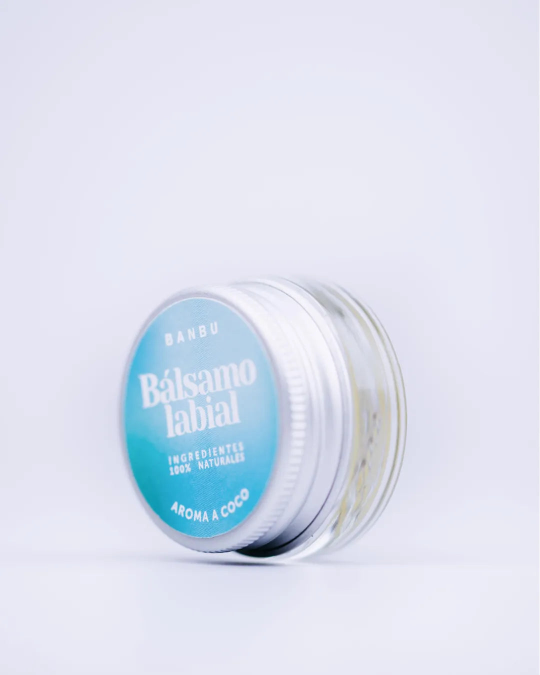Bálsamo labial ecológico Banbu de coco en tarro de vidrio con tapa metálica azul sobre fondo blanco.