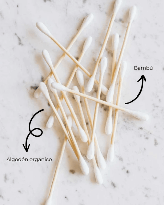 Bastoncillos Banbu de bambú y algodón orgánico sobre fondo de mármol blanco. Etiquetados con flechas explicativas.