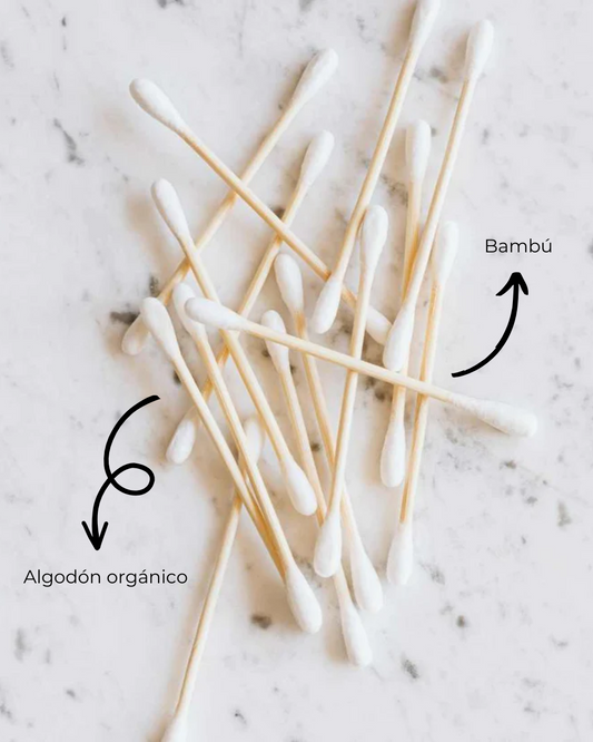 Bastoncillos Banbu de bambú y algodón orgánico sobre fondo de mármol blanco. Etiquetados con flechas explicativas.