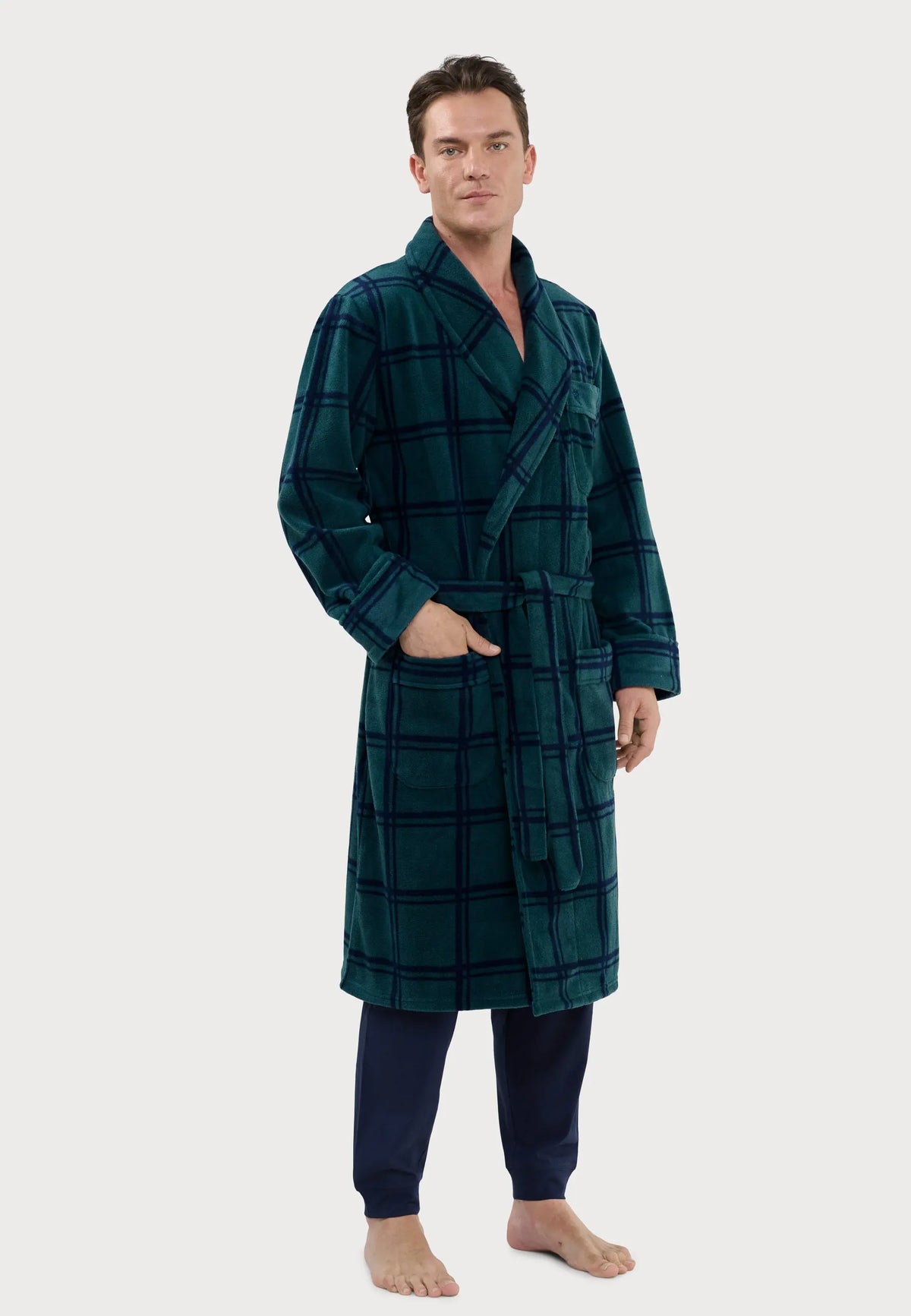 Bata de hombre forro polar verde con cuadros azul marino, cinturón, bolsillos y cuello solapa. Modelo posando de pie.