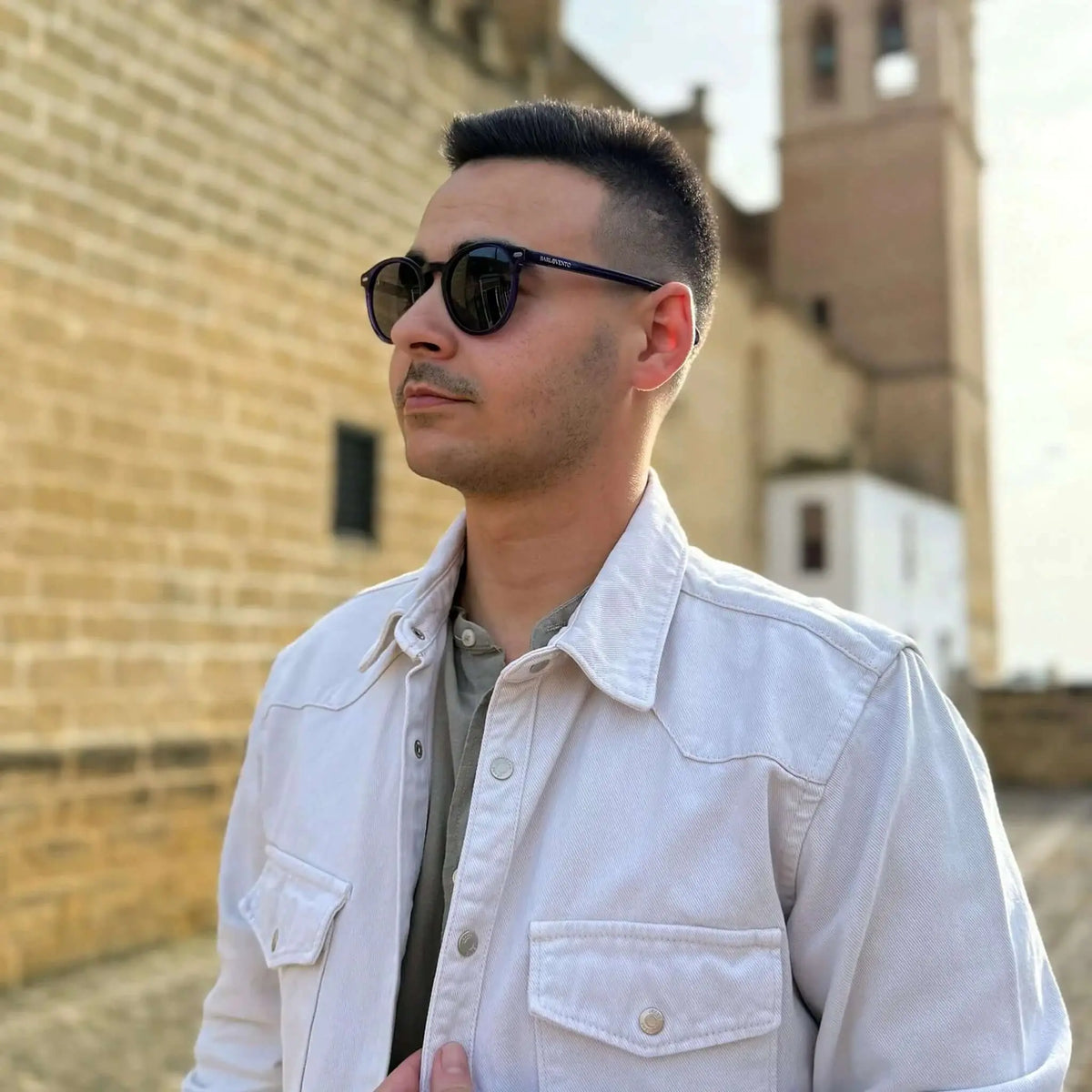 Gafas de sol de montura redonda en tono morado oscuro con cristales oscuros, estilo clásico y elegante.