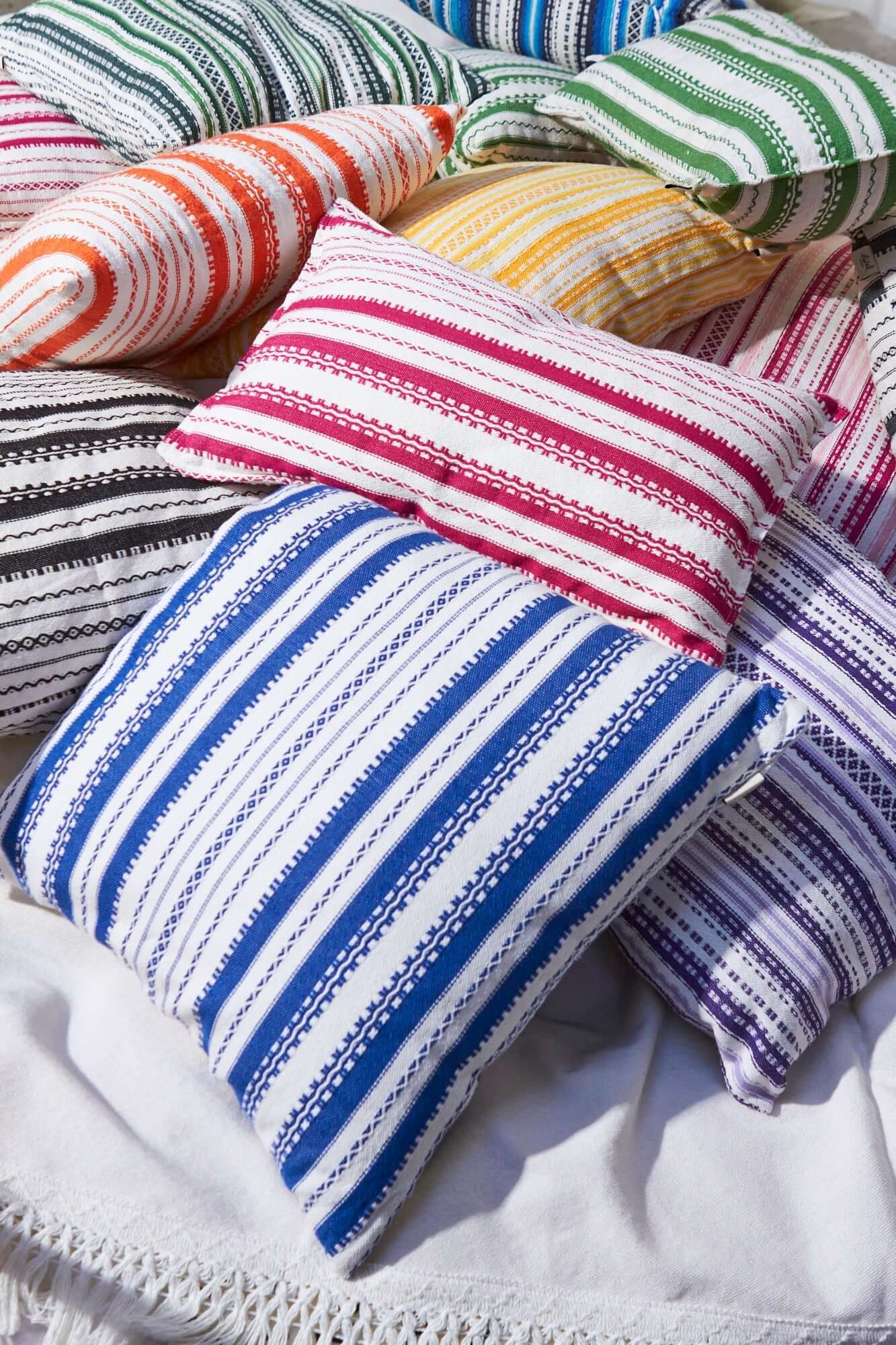 Funda de cojín rectangular de 30x50 cm con tejido de estilo alpujarra, rayas rojas y blancas y detalles geométricos.