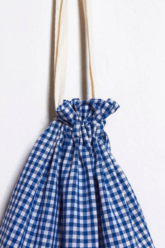 Panera de tela con estampado de cuadros vichy en azul y blanco, con cierre fruncido y asas de algodón crudo.